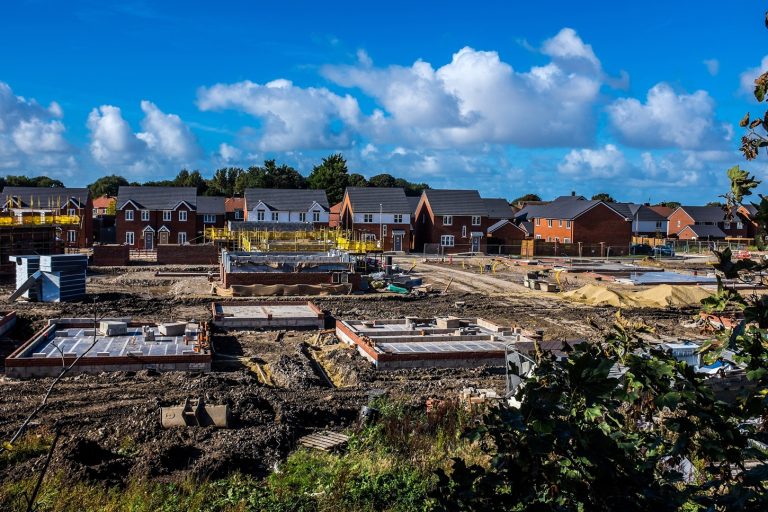 Accompanying image of new houses being built with foundations laid and newly built houses in the background.